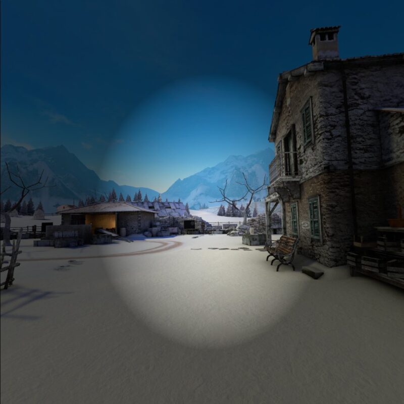 Gameplay of Winter Warrior with a vignette overlayed, which casts a semi-transparent darkness to the edges of the screen. Most of the scene is affected, showing a snowy courtyard with two distressed buildings, one to the right and one ahead. There are also leafless trees and many crates around the edges of the courtyard. In the distance coniferous trees can be seen, and beyond them large snowy mountains.