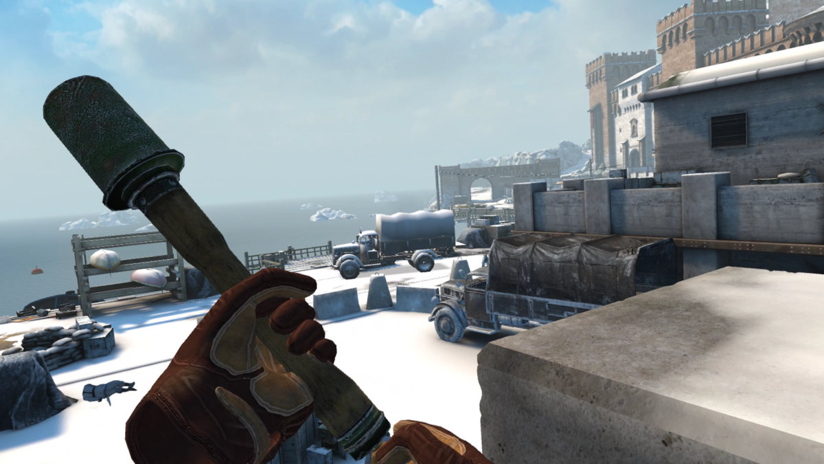 You are holding a grenade, ready to pull the pin. An enemy lies dead on the floor nearby and two vehicles ahead are primed for an explosive. A frozen sea and stone battlement feature in the background.